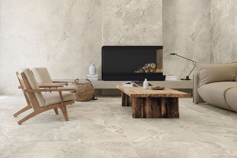 Wohnzimmer mit Bodenfliesen in Steinoptik, Sesseln, Kamin und Holztisch