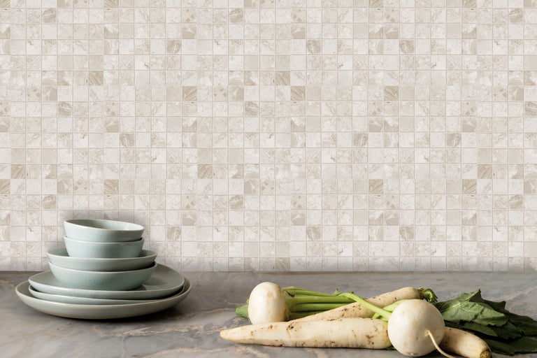 Dekorative Mosaikfliesenwand mit Geschirr und Gemüse auf einer Arbeitsplatte.