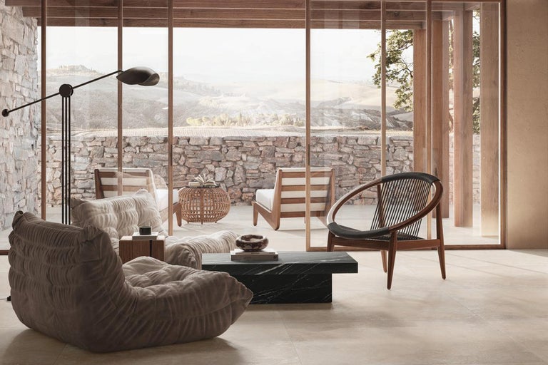 Heller Wohnraum mit großem Fenster, Sessel und Natursteinwand