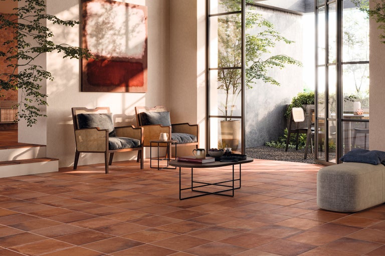 Wohnzimmer mit Terrakottafliesen, Rattansesseln und Blick in den Garten