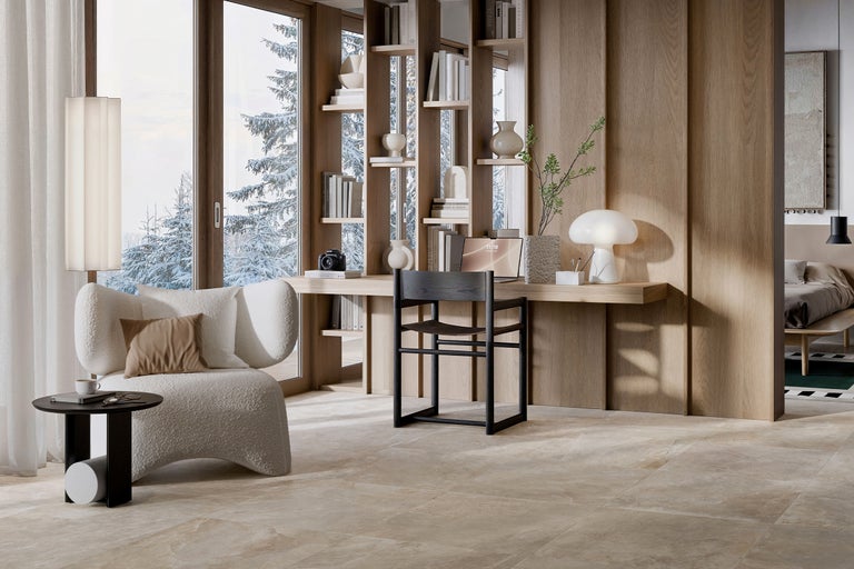 Helles Arbeitszimmer mit Sessel, Schreibtisch und Bücherregal vor einem Fenster mit Winterlandschaft