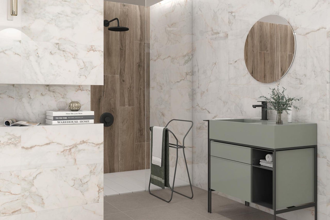 Modernes Badezimmer mit Wandfliesen in Marmoroptik und Holzoptik, Waschtisch mit grünem Unterschrank und runder Spiegel.