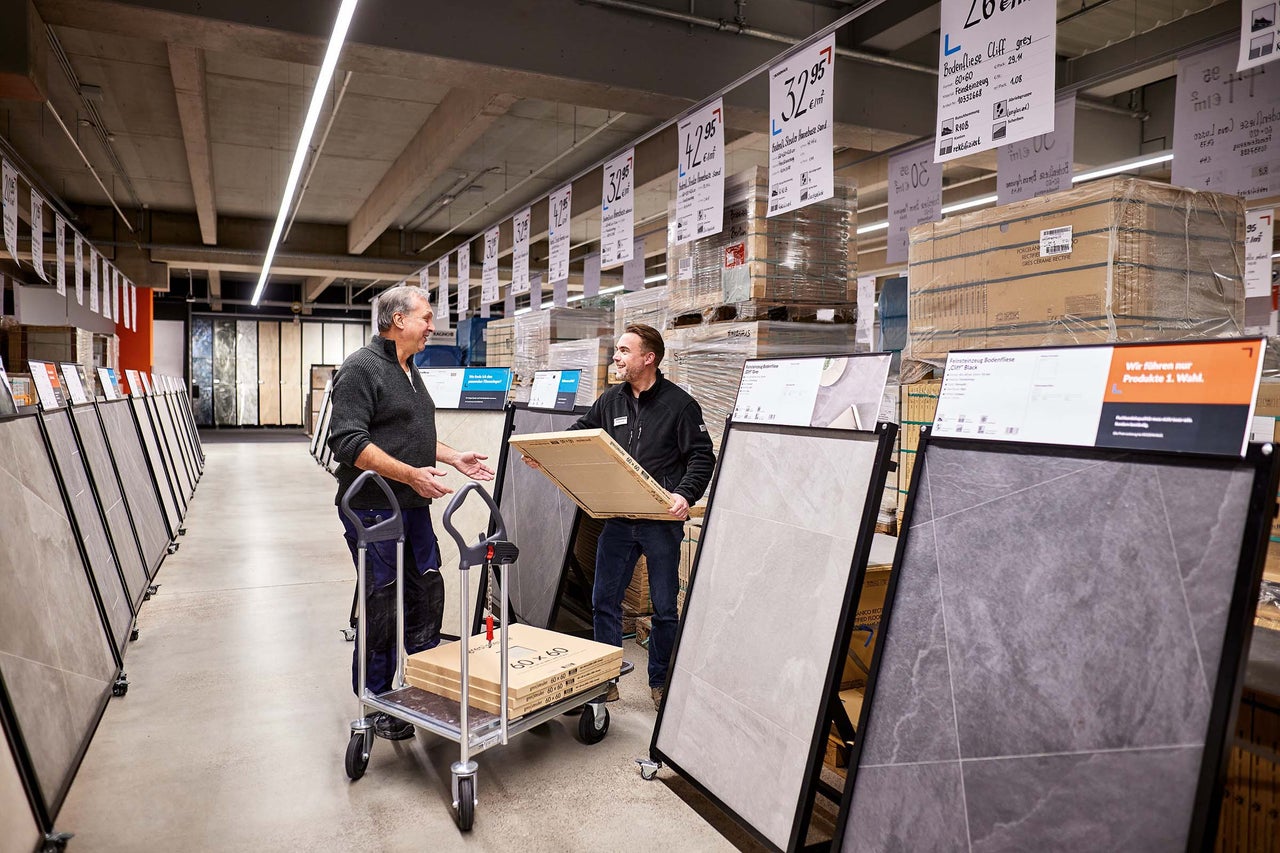 Kunden und Mitarbeiter im Gespräch vor Fliesenständern im Hornbach Markt