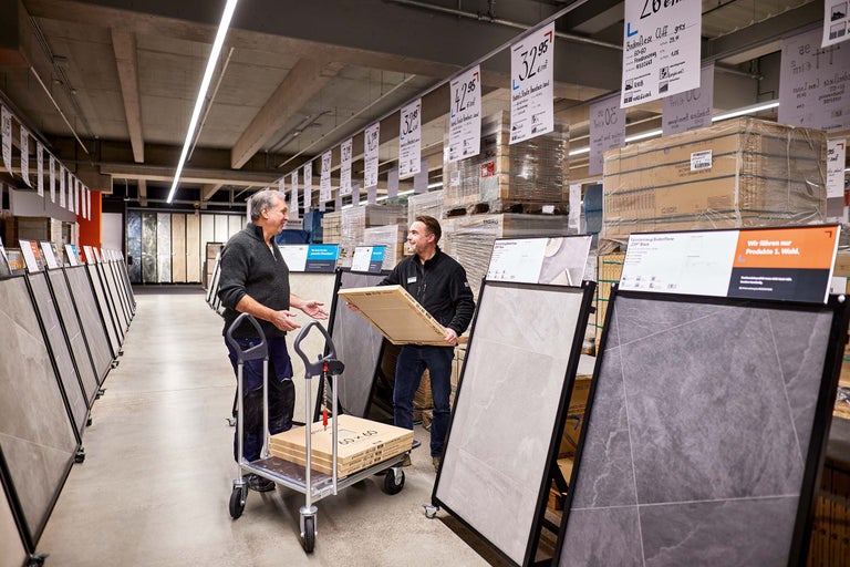 Kunden und Mitarbeiter im Gespräch vor Fliesenständern im Hornbach Markt