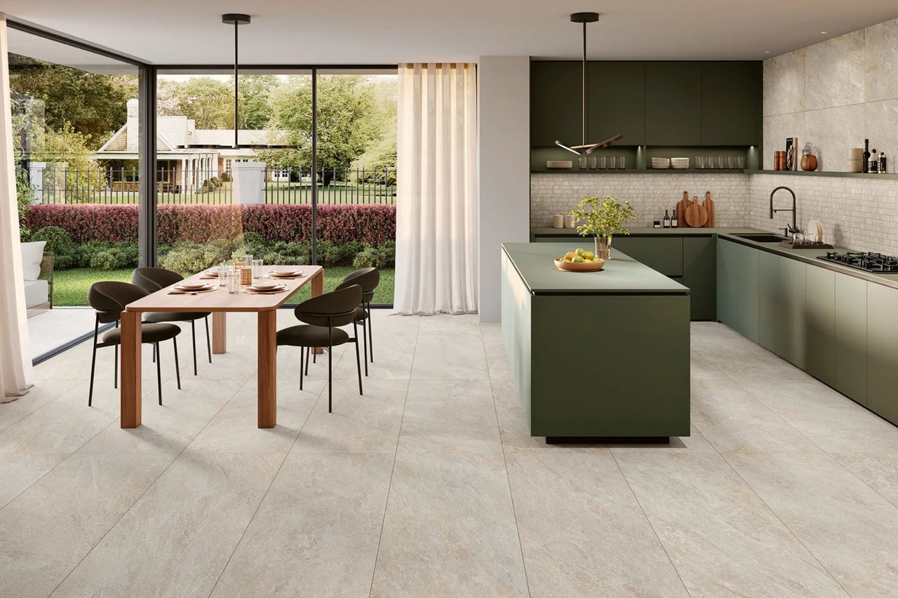 Großzügige, helle Wohnküche mit großformatigen Bodenfliesen in Steinoptik, dunkelgrünen Küchenschränken, Kochinsel und einem hölzernen Esstisch.