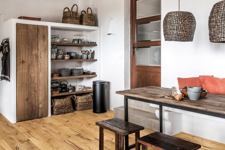 Küchenszene mit Holztisch, Stühlen, Regalen, Schränken und dekorativen Elementen