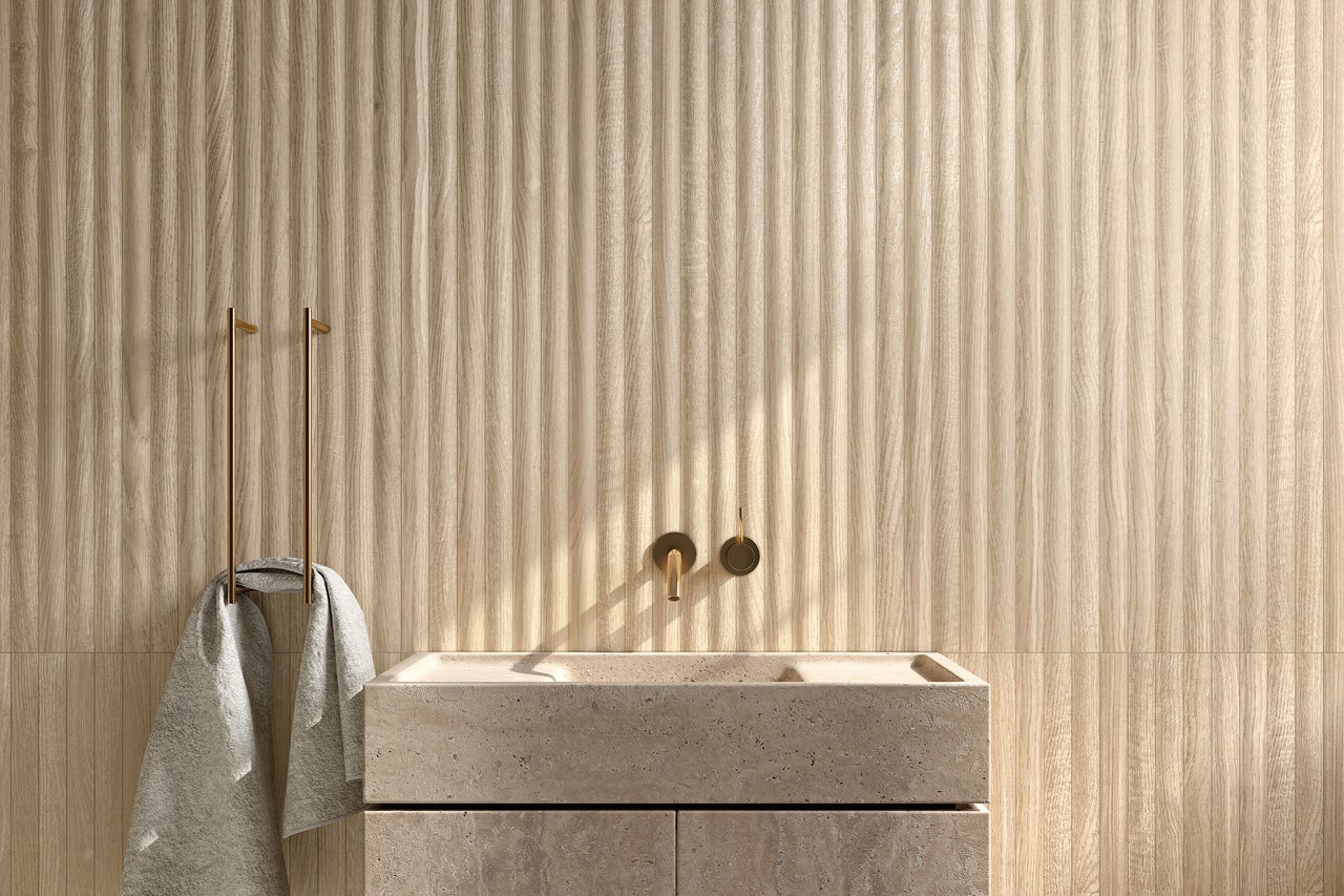 Badezimmer mit Waschtisch aus Stein, Armatur und Handtuchhalter vor einer Wand mit Holzpaneelen