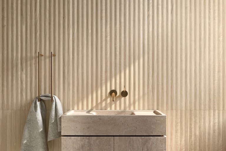 Badezimmer mit Waschtisch aus Stein, Armatur und Handtuchhalter vor einer Wand mit Holzpaneelen