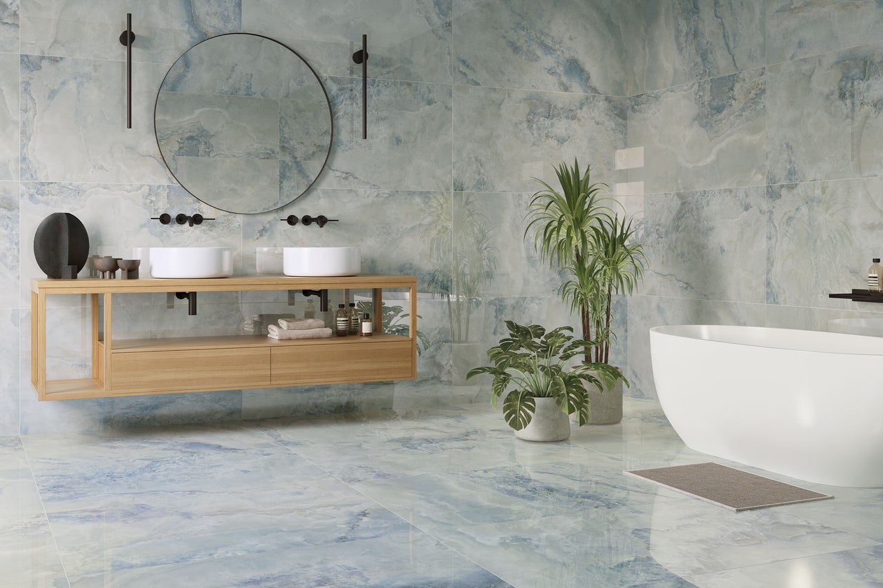 Modernes Badezimmer mit großformatigen Fliesen in blau-weißer Marmoroptik an Wand und Boden, Holzwaschtisch und freistehender Badewanne.