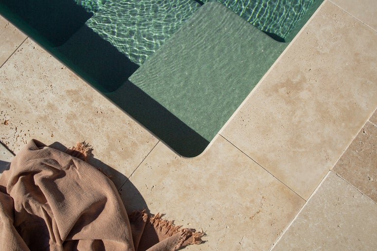 Schwimmbeckenumrandung aus Travertin mit Badetuch