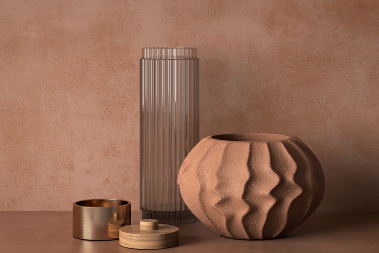 Dekoratives Arrangement mit einer hohen Glasvase, einer Kugelvase mit Textur und einer Dose mit Deckel.