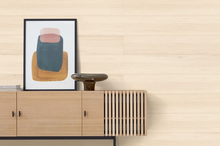 Moderne Wandpaneele in heller Holzoptik in einem hellen Wohnzimmer mit einem Sideboard aus Holz und abstrakter Kunst.