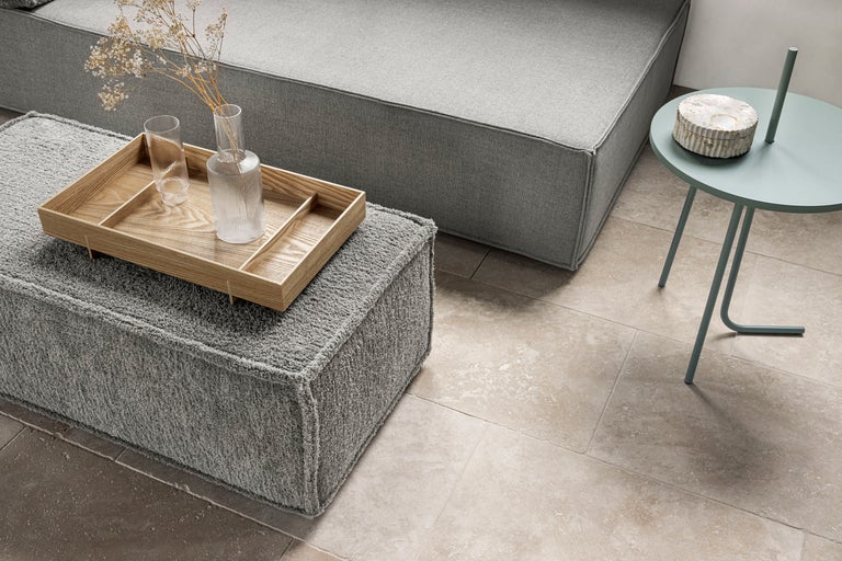 Wohnzimmer Szene mit grauem Sofa, grauem Hocker, Holztisch und Dekoration