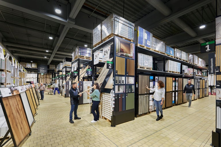 Gang im Hornbach Baumarkt mit Regalen voller Bodenbeläge wie Vinyl, Parkett und Paneele.