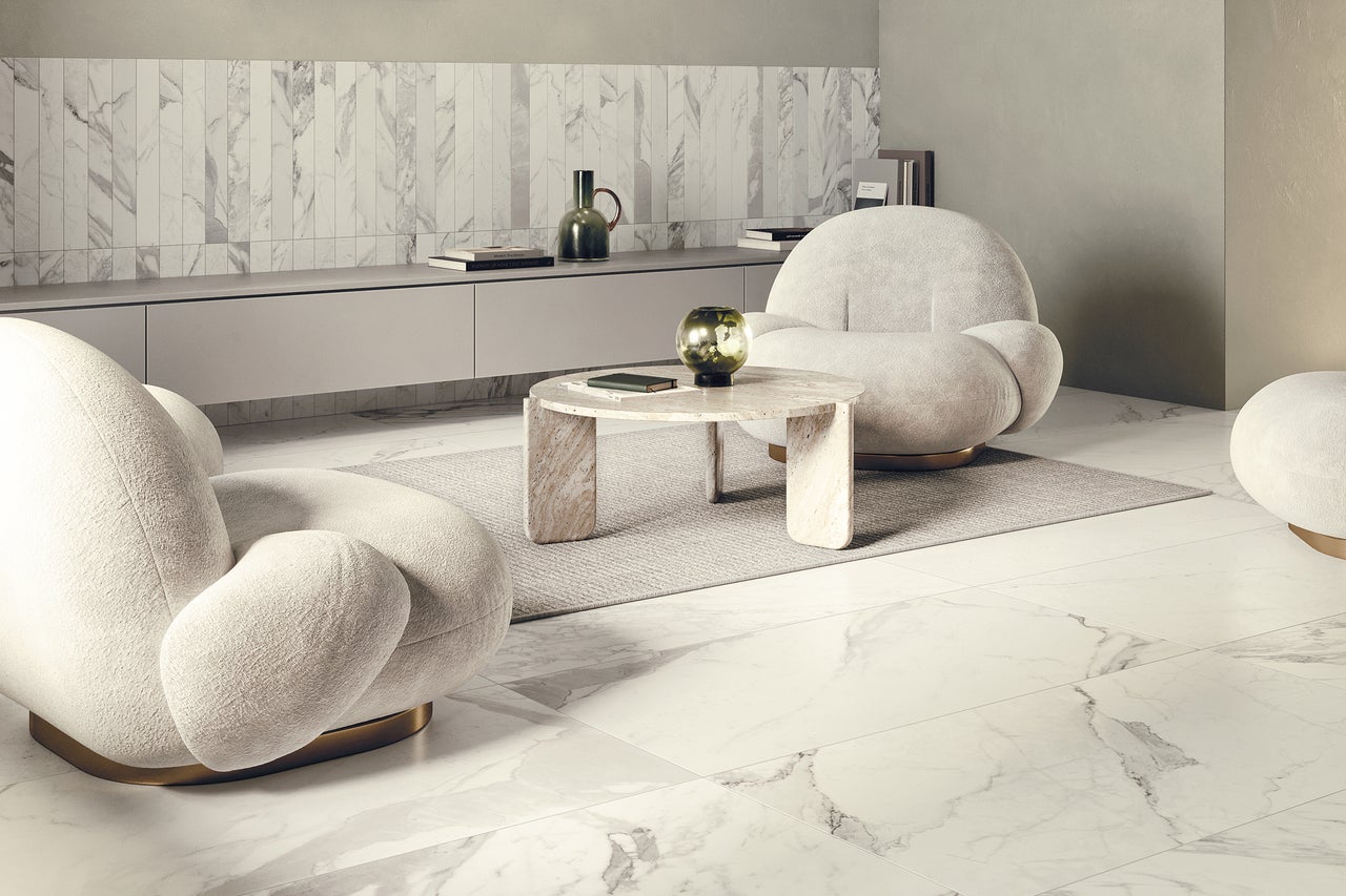 Heller Wohnraum mit Fliesenboden in Marmoroptik, zwei Sesseln, Teppich und Couchtisch
