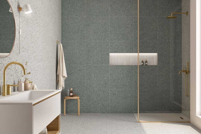 Modernes Badezimmer mit Terrazzo Fliesen an Wand und Boden, begehbarer Dusche mit goldenen Armaturen und einem schlichten Waschtisch.