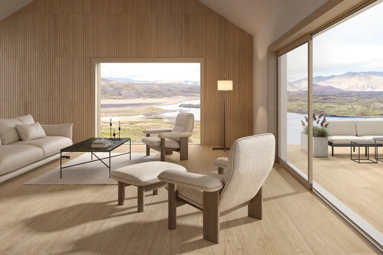 Heller Wohnraum mit Sofa, Sessel und Blick auf die Landschaft