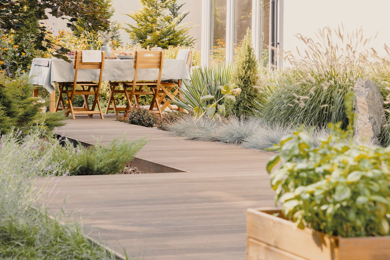 Gartenszene mit Holzterrasse, Esstisch und Stühlen