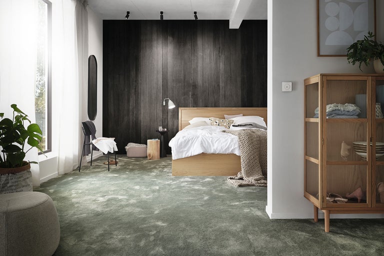 Modernes Schlafzimmer mit grünem Teppichboden, einem Holzbett, dunkler Wandvertäfelung und einer Vitrine aus Holz.