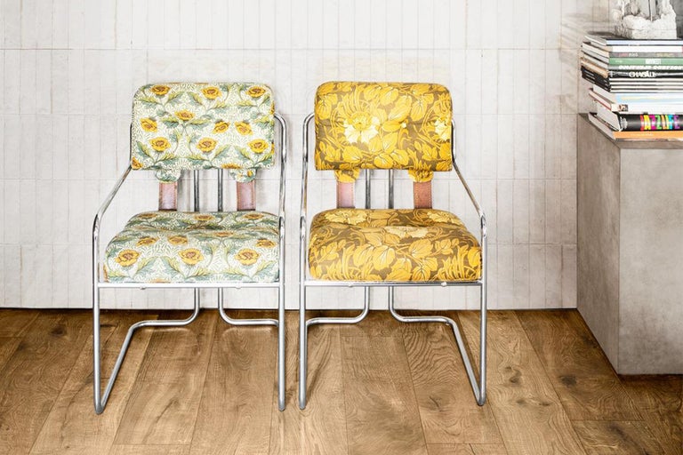 Zwei Stühle mit floralen Mustern und Metallgestell vor einer Wand