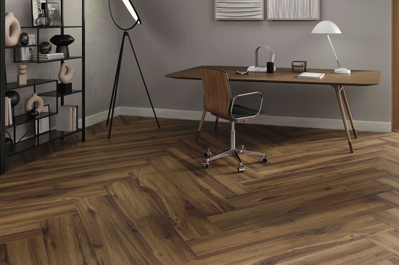 Büro mit Schreibtisch, Bücherregal und dunklem Holzboden im Fischgrätmuster