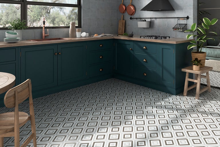 Küchenansicht mit blaugrauer Küchenzeile, Holz-Arbeitsplatte und gemusterten Bodenfliesen