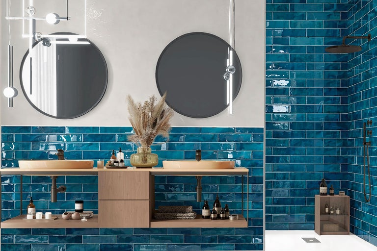 Modernes Badezimmer mit blau glasierten Wandfliesen, zwei runden Spiegeln und einem hölzernen Waschtisch mit zwei Aufsatzbecken.