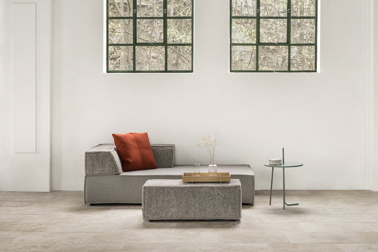 Helles Interieur mit Sofa, Ottomane, Beistelltisch und Fenstern für eine freundliche Wohnatmosphäre