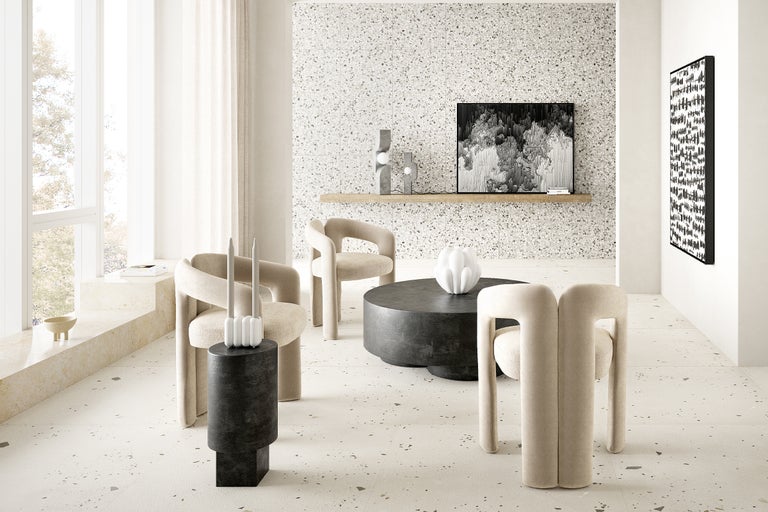 Heller Wohnraum mit Terrazzoboden, Sesseln, Couchtisch und Dekoration