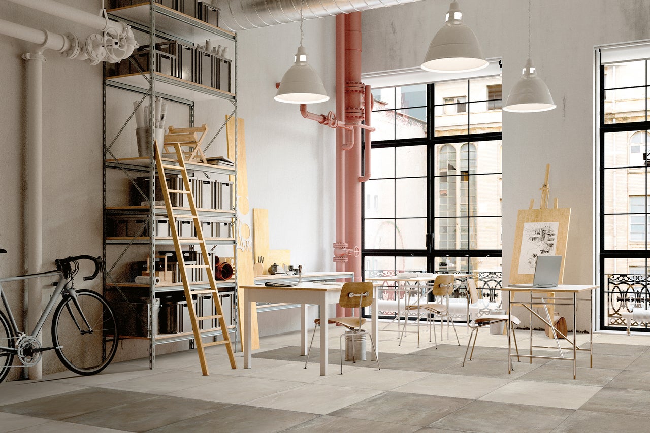 Heller Raum mit Regalen, Leiter, Tischen, Stühlen, Fahrrad und großen Fenstern