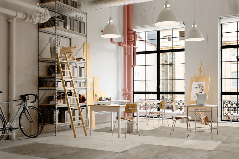 Heller Raum mit Regalen, Leiter, Tischen, Stühlen, Fahrrad und großen Fenstern