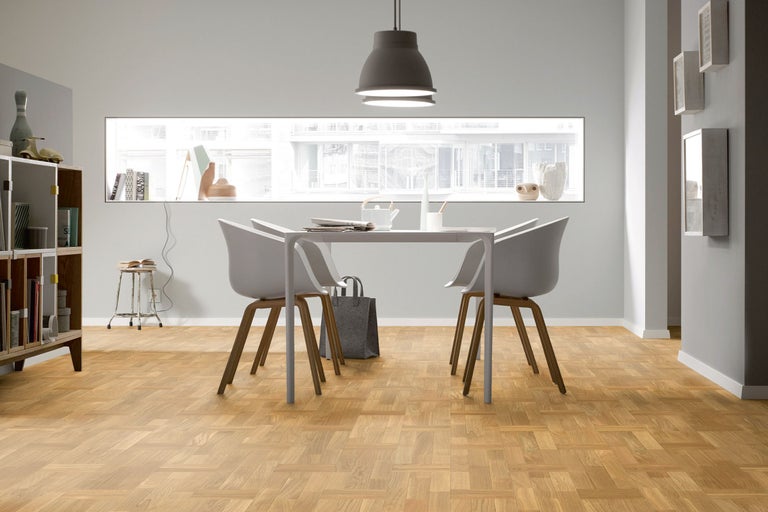 Heller Raum mit Esstisch, Stühlen und Parkettboden.