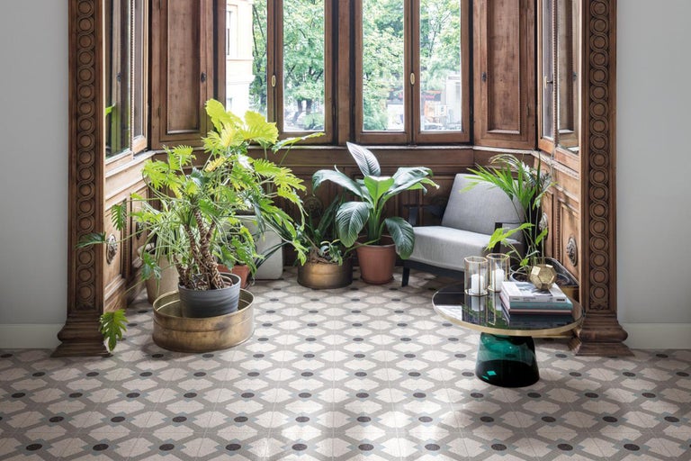 Heller Raum mit gemustertem Fliesenboden, Pflanzen und Holzelementen.
