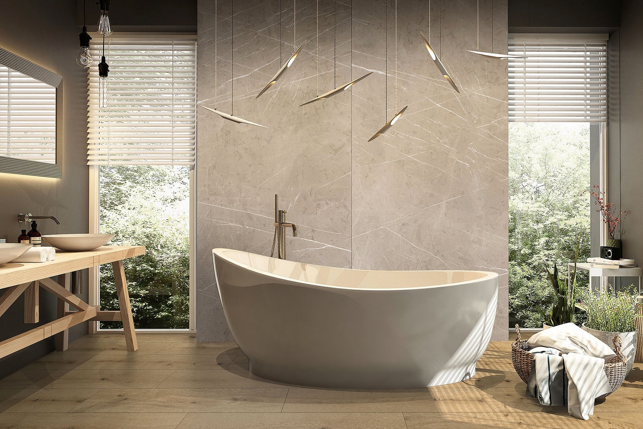 Modernes Bad mit freistehender Wanne, Wandfliesen in Marmoroptik, Boden in Holzoptik und Waschtisch aus Holz vor großen Fenstern.