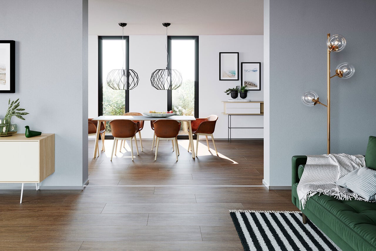 Modernes, helles Wohnzimmer mit dunklem Boden in Holzoptik, geräumiger Essbereich mit braunen Stühlen und geometrischen Pendelleuchten.