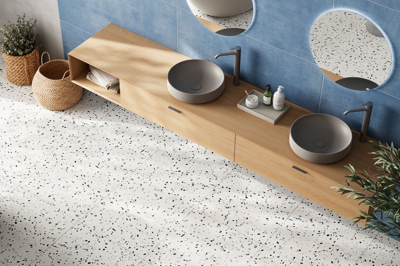 Modernes Badezimmer mit Doppelwaschtisch aus Holz, grauen Aufsatzbecken, blauen Wandfliesen und Bodenfliesen in Terrazzo-Optik.