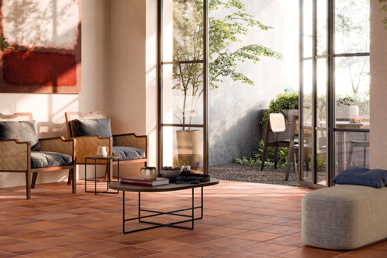 Heller Wohnraum mit Terrakottafliesen, Rattansesseln und Blick in den Garten