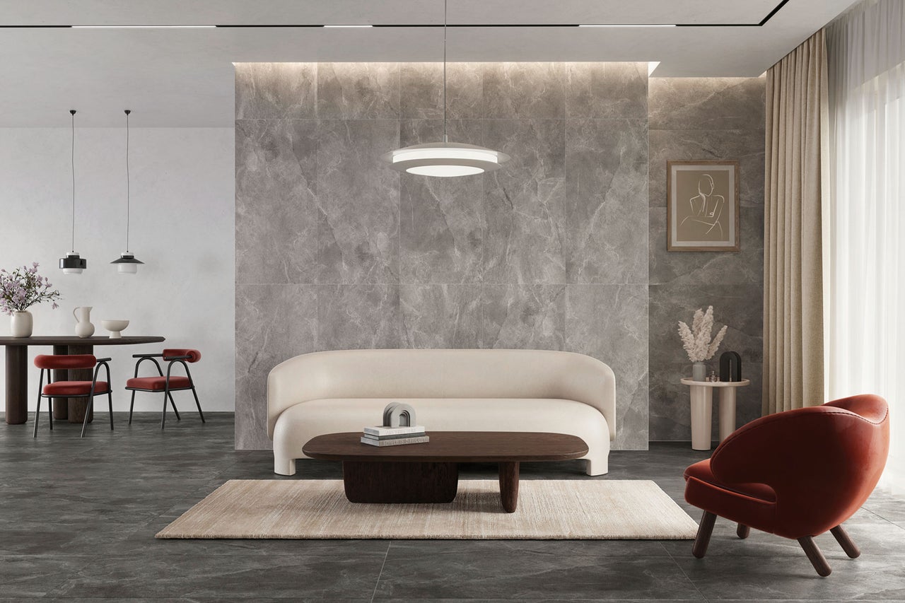 Modernes Wohnzimmer mit Wandfliesen in Marmoroptik, dunklen Bodenfliesen in Steinoptik, hellem Sofa, dunklem Holztisch und roten Sesseln.