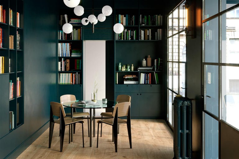 Helles Esszimmer mit Bücherregalen, rundem Glastisch und Holzstühlen