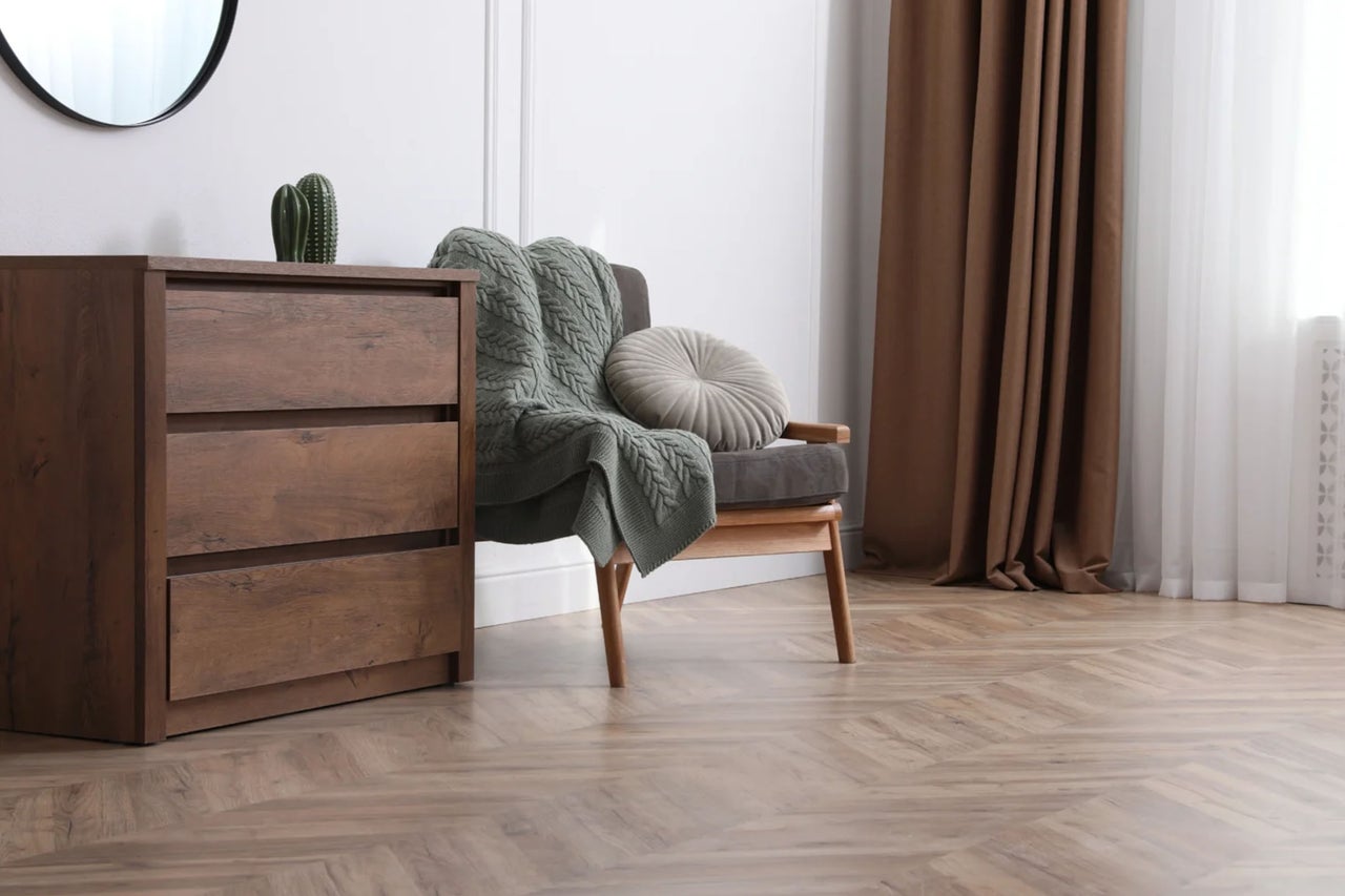 Wohnzimmer mit Kommode, Sessel mit Decke und Vorhängen