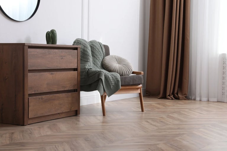 Wohnzimmer mit Kommode, Sessel mit Decke und Vorhängen