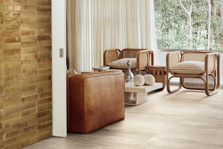 Heller Wohnraum mit Rattansesseln, Ledersofa und Fliesen