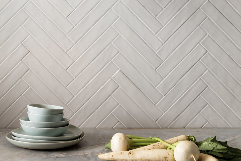 Wandfliesen im Fischgrätmuster mit Geschirr und Gemüse auf einer Arbeitsfläche