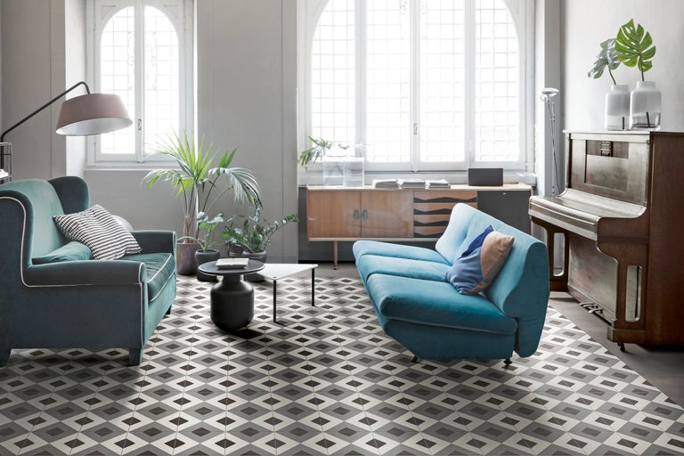 Wohnzimmer mit Sofa, Sessel, Tisch, Kommode, Klavier und Bodenfliesen im geometrischen Muster