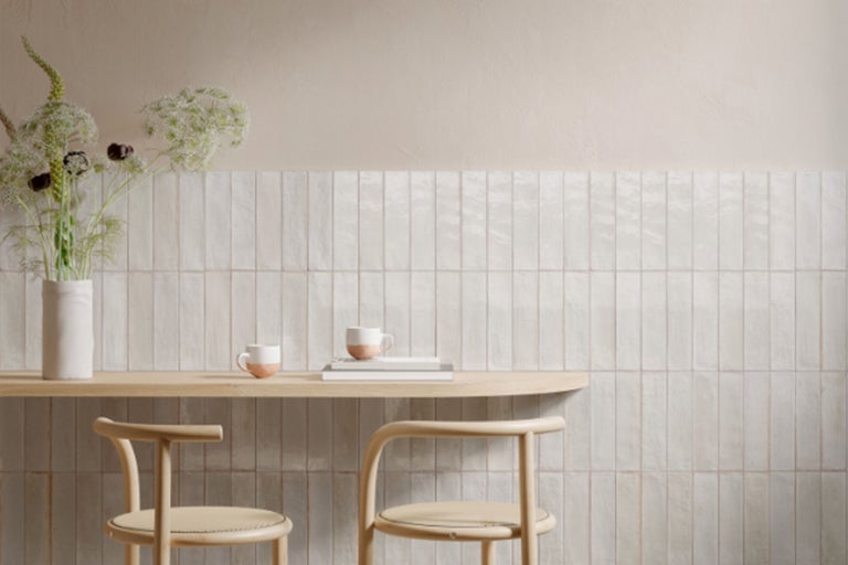 Heller Raum mit Keramikfliesen an der Wand, Holztisch und Stühlen