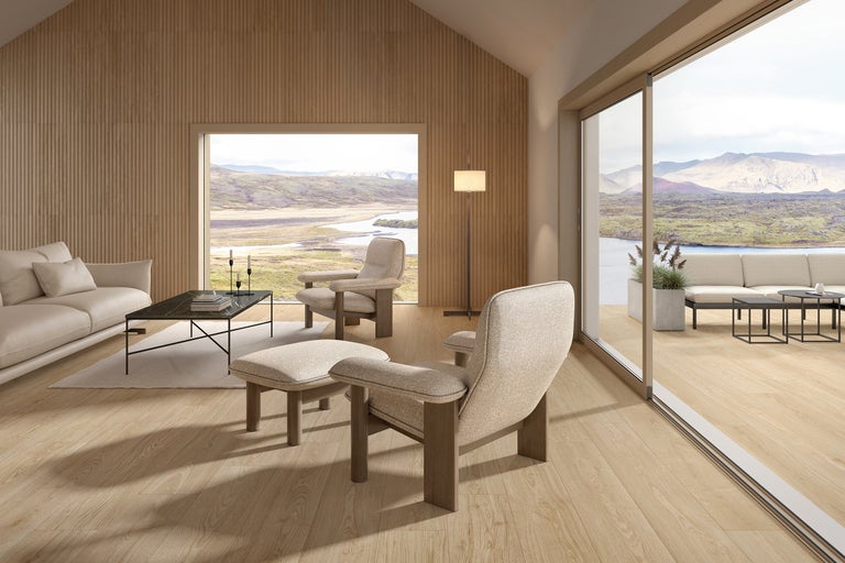 Heller Wohnraum mit Sofa, Sesseln, Teppich und großem Fenster mit Aussicht