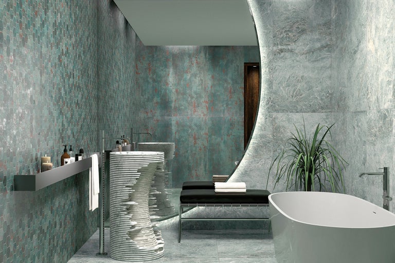 Modernes Badezimmer mit freistehender Badewanne, skulpturalen Waschbecken, großem runden Spiegel und Wandfliesen in Mosaik- und Natursteinoptik.