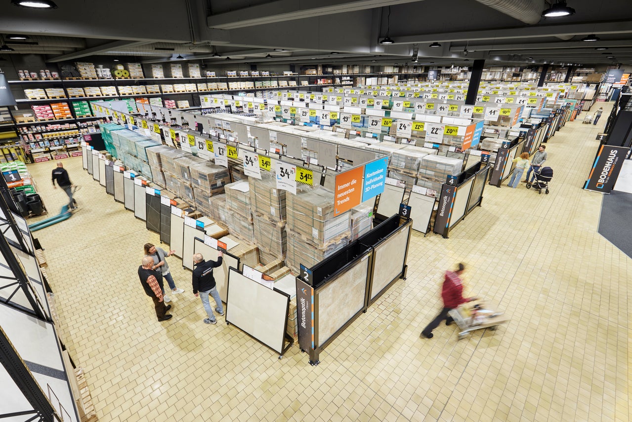 Große Halle im Hornbach Baumarkt mit Fliesenausstellung, Preisschildern und Kunden.