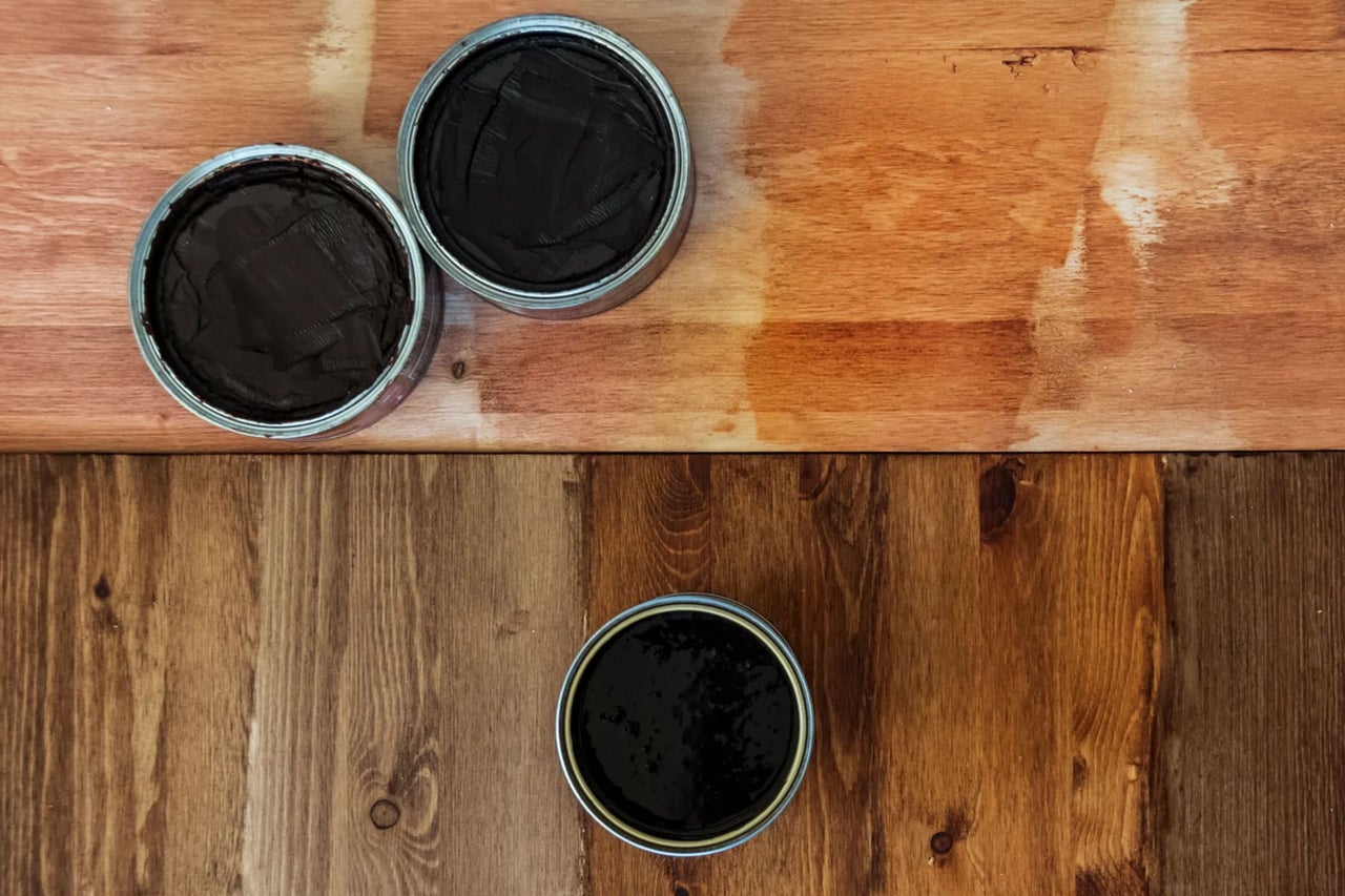 Drei Farbdosen auf unterschiedlichen Holzoberflächen