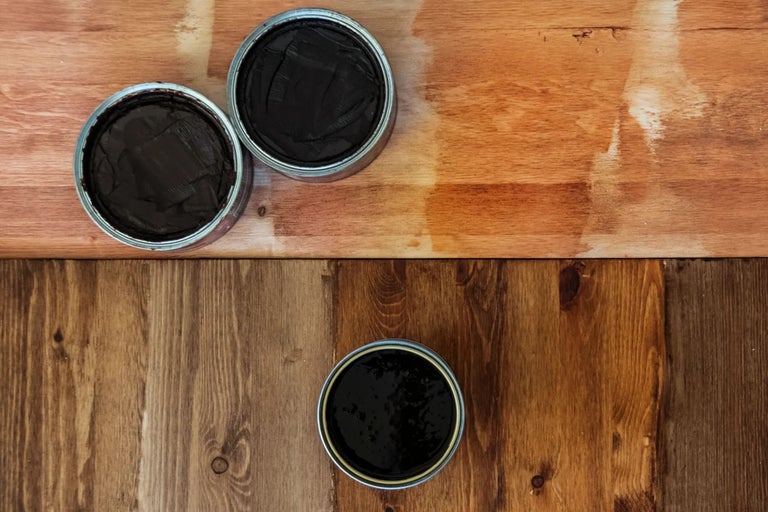 Drei Farbdosen auf unterschiedlichen Holzoberflächen